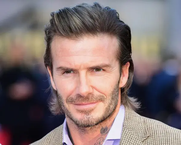 Hombre con pelo semi largo hombre liso, barba cuidada y traje a cuadros.